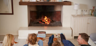 Family Sitting On Sofa In Lounge Next To Open Fire