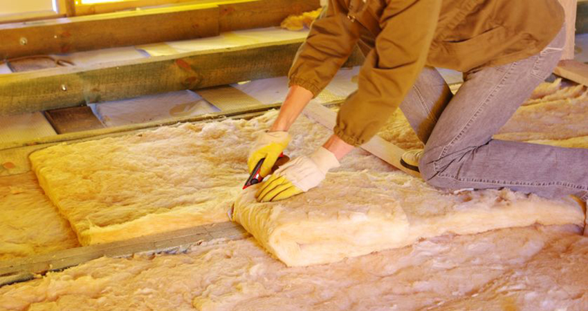 construction worker thermally insulating house attic with glass wool